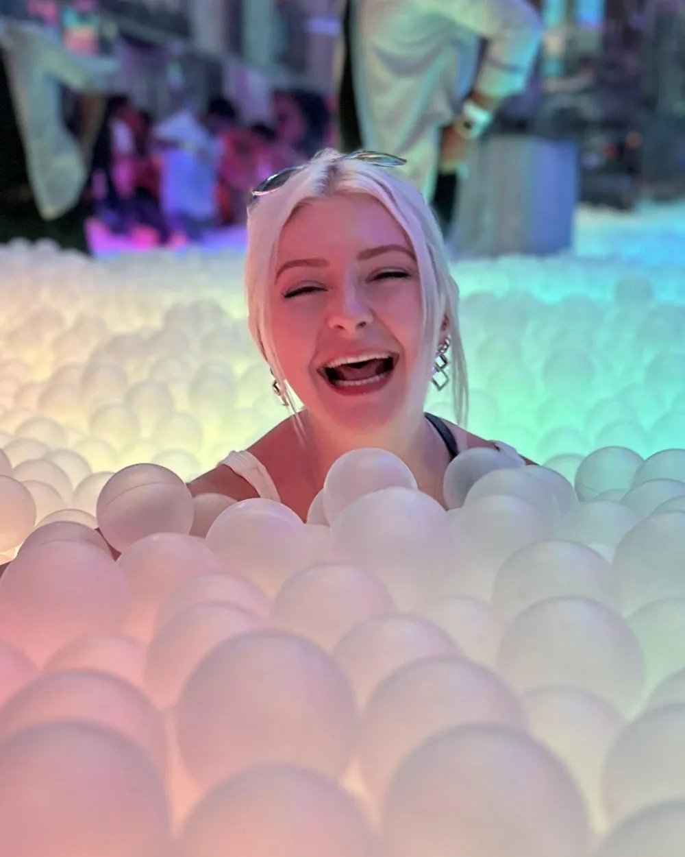 Molly laughing in a glowing ball pit
