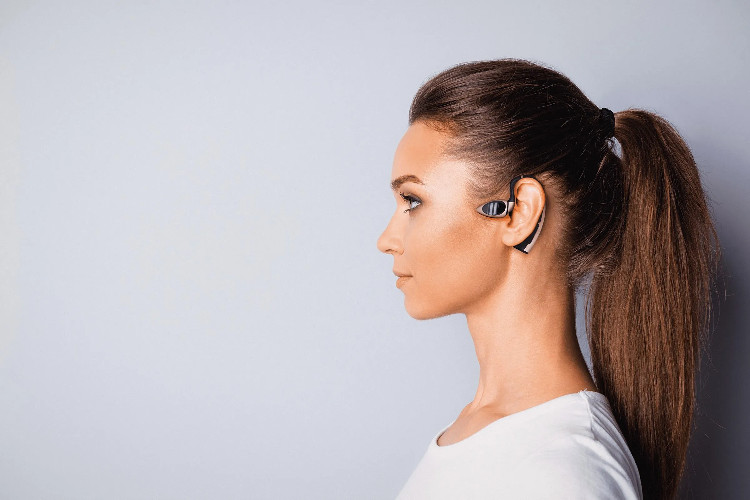 A woman in profile wearing the Heron earpiece behind her ear
