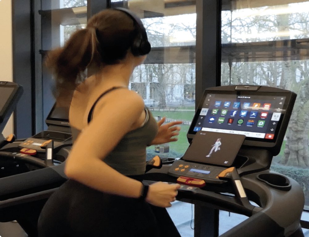 A participant running with headphones on, watching the treadmill screen